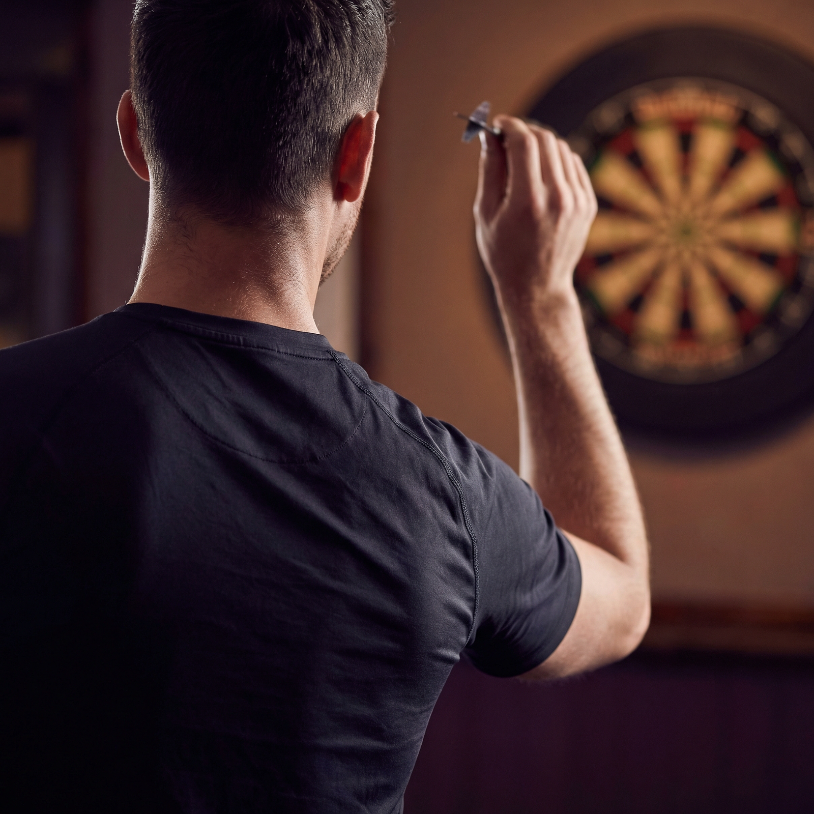 A darts player preparing to release a dart